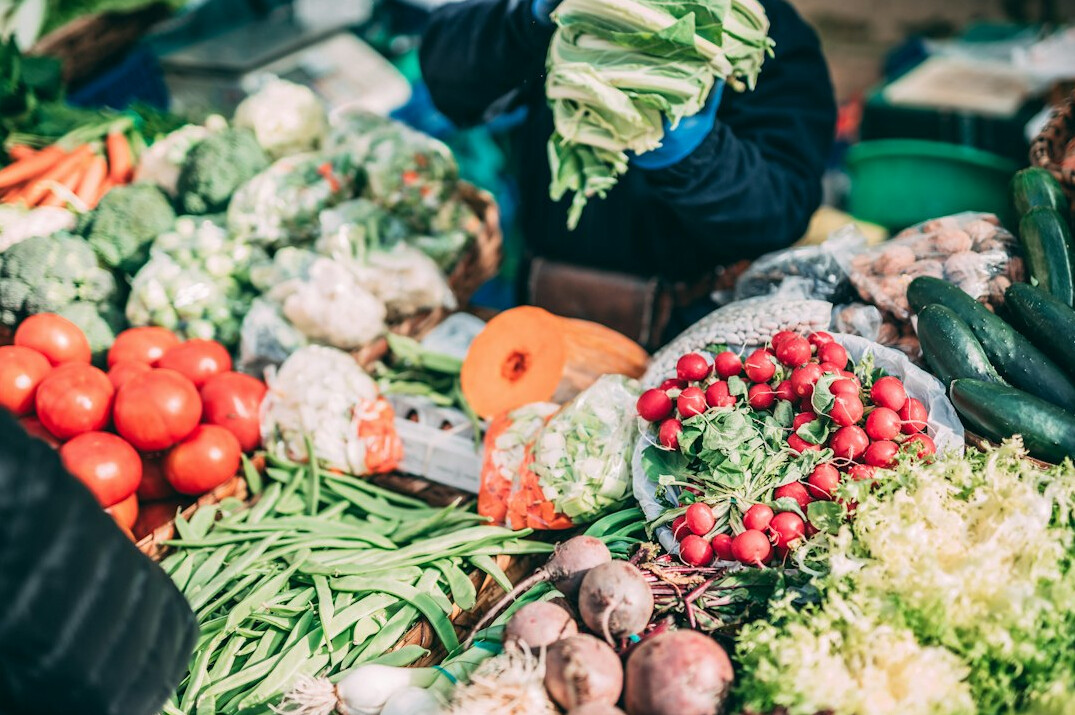 An elderly Chilean market vendor arranging fresh produce at a street market